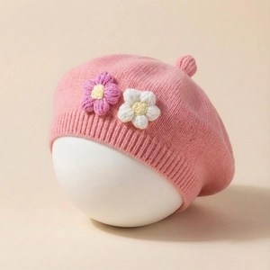 Detailed view of pink knitted baby beret with handmade floral accents and top pompom