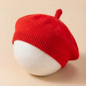 Detailed texture of red knitted baby beret with ribbed edge and top stem detail