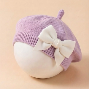 Détail du béret tricoté pour bébé violet clair avec un grand nœud décoratif crème