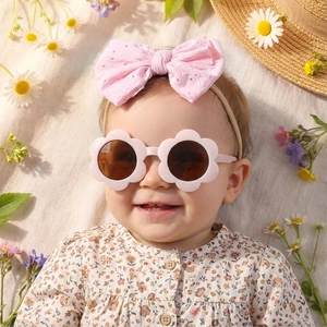 Détail de lunettes fleurs roses et bandeau dentelle avec vêtements bébé à fleurs