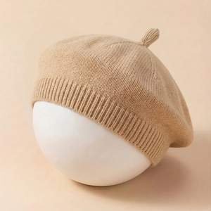 Detail of soft knitted baby beret in beige with ribbed edge and top stem ornament