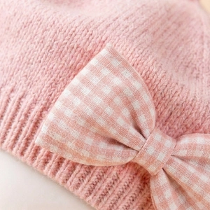 Macro di berretto per neonati in maglia rosa con fiocco decorativo a quadretti