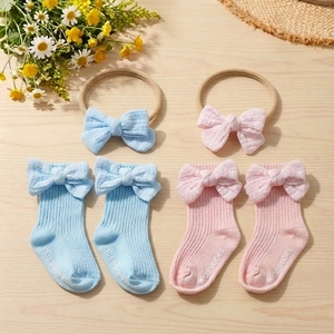 Detail of ribbed cotton baby socks with bows and anti-slip grips on wooden surface