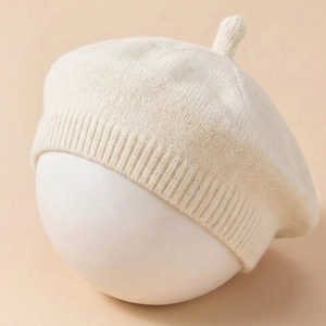 Detailed close-up of cream knit baby beret with textured ribbing and top stem detail