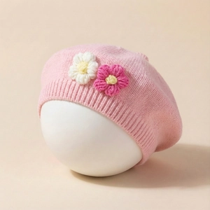 Detail of pink knitted baby beret with handmade crochet flowers in white and rose colors