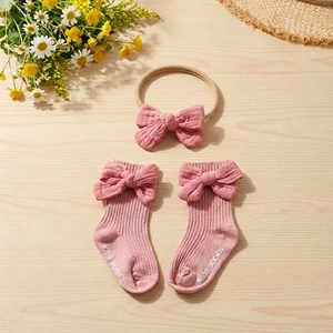 Detail of baby cotton bow headband and matching anti-slip socks with ribbed texture