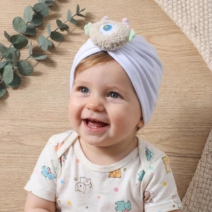 Dettaglio del cappello a turbante bianco per neonati con occhi di mostro in peluche morbido
