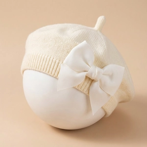 Détail du béret en tricot pour bébé avec un grand nœud blanc et une texture côtelée douce