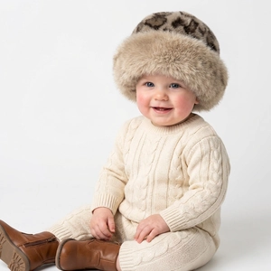 Detail of infant leopard plush hat with cream knitted romper and brown boots