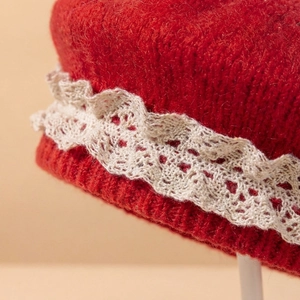 Détail du béret tricoté rouge pour bébé avec bordure en dentelle blanche et maille épaisse