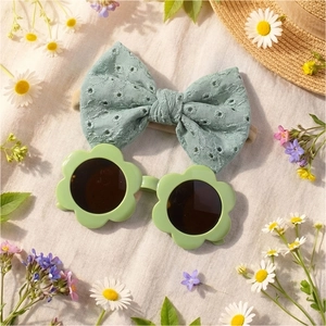 Détail de lunettes de soleil fleur vert sauge et bandeau brodé sur tissu marguerite