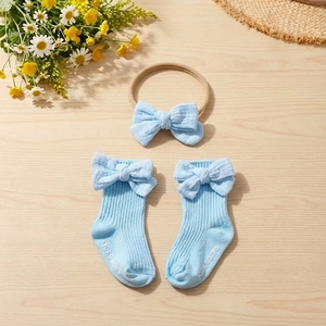 Detail of light blue cotton ribbed baby headband and socks with delicate bow accents