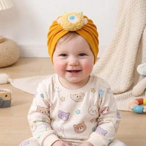 Dettaglio cappello arancione neonato con mostro 3D e design con nodo in morbido cotone