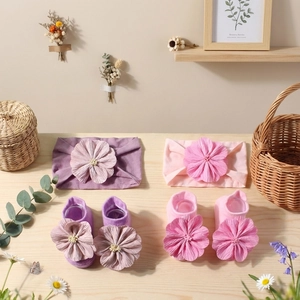 Detail von Baby-Stirnband und Socken-Set mit Blumen aus weichem lila und rosa Strick