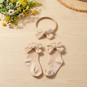 Close-up of beige cotton baby headband and non-slip socks set with cute bow detailing