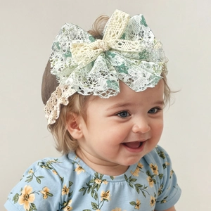 Detailaufnahme eines Baby-Spitzenstirnbandes mit großer grüner Blumenschleife am Modell