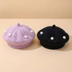 Detail of soft knitted baby berets in purple and black with white 3D polka dots