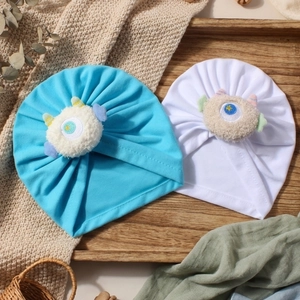 Dettaglio di cappelli in maglia per neonati con mostri di peluche su sfondo nordico