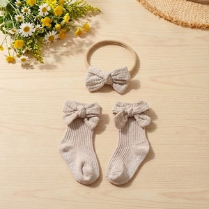Baby cotton headband and bow socks set on wooden desk with floral decor detail