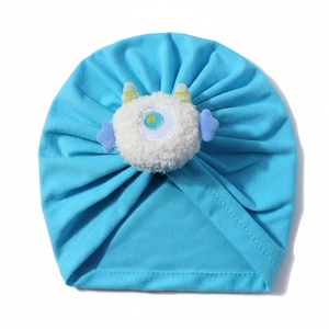 Dettaglio del cappello blu neonato con bambola mostro di peluche e maglia morbida