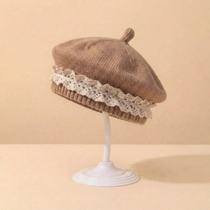 Détail d'un béret tricoté pour bébé avec dentelle blanche et tige sur un support