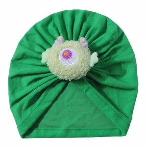 Dettaglio del turbante neonato verde brillante con mostro di peluche e tessuto elastico