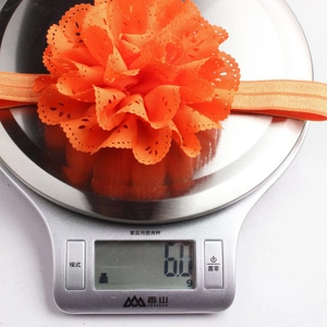 Details eines orangefarbenen Blumen-Baby-Stirnbands auf einer Digitalwaage mit 6,0 g Gewicht