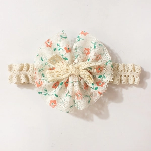 Detail eines weißen Baby-Spitzenstirnbandes mit Blumendruck-Schleife und weicher Textur