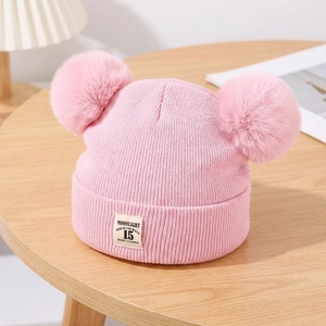 Close-up of pink knit baby hat featuring double faux fur pom-poms and MOONLIGHT label