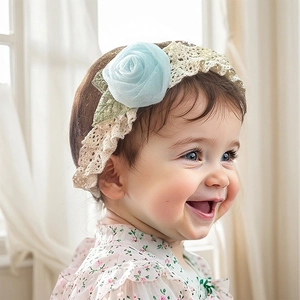 Détail du bandeau bébé en dentelle blanc cassé avec une rose bleue et feuilles vertes