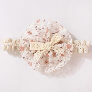Detailansicht eines Baby-Stirnbandes aus Spitze mit Blumendruck und Schleife