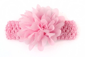 Détail d'une fleur en mousseline rose sur un bandeau en dentelle élastique pour bébé