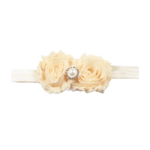 Détail d'un bandeau pour bébé avec fleurs en mousseline, perle et strass brillants