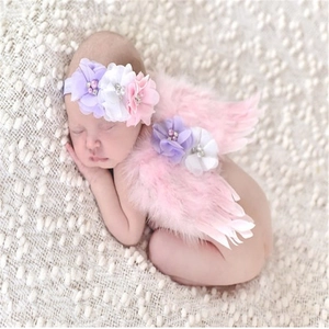 Detail of pink feather angel wings and floral headband on a sleeping newborn baby