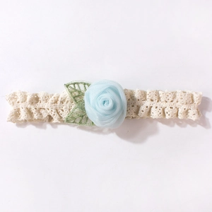 Détail du bandeau en dentelle pour bébé avec rose en maille bleu clair et feuilles brodées