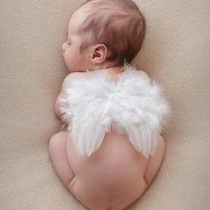 Newborn baby photography prop featuring soft white angel feather wings on knitted fabric
