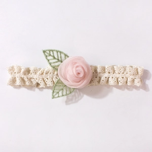 Détail du bandeau en dentelle pour bébé avec rose en soie rose et broderie de feuilles