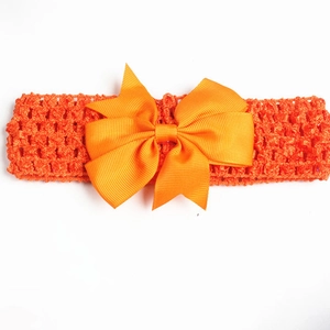 Detailed view of an orange crochet baby headband with a large grosgrain ribbon bow
