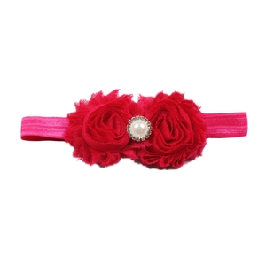 Détail d'un bandeau bébé rouge avec roses en mousseline perle blanche et strass brillants