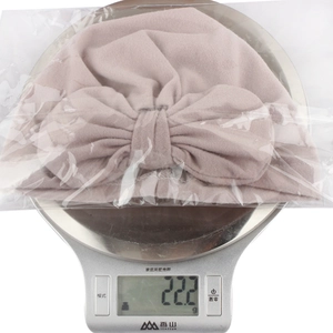 Detail showing the lightweight 22.2g baby bow hat in packaging on a scale for weight verification