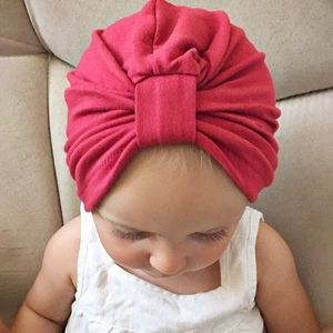 Gros plan détaillé d'un bonnet turban bébé rouge rose avec nœud et plis doux