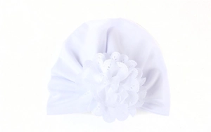 Détail du bonnet blanc pour bébé avec fleur en dentelle ajourée et tissu doux extensible
