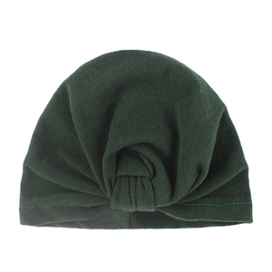 Detail of soft dark green knitted turban hat featuring a handcrafted front knot design