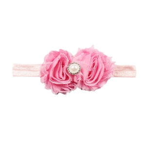 Détail de fleurs en mousseline rose bébé avec perle et strass sur un bandeau élastique