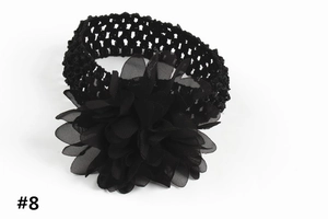 Détail d'un bandeau pour bébé en crochet noir avec une grande fleur en tissu mousseline