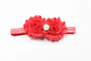 Détail de fleurs en mousseline rouge avec boucle perle et strass sur bandeau bébé