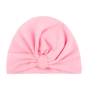 Pink bohemian style baby turban hat with twisted knot design on white background