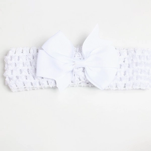 Close-up of a soft white crochet baby headband featuring a large grosgrain ribbon bow