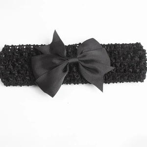 Detail view of a black elastic crochet baby headband with a large grosgrain ribbon bow