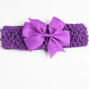 Detail view of purple crochet headband with a large ribbed ribbon bow for baby girls